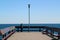 Man leaning next to Single Lantern at the end of a landing stage on a clear blue sky