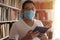 Man learning studying reading book in library during coronavirus covid19 pandemic, wearing protective medical face mask