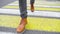 A man in leather shoes crosses the road at a pedestrian crossing.
