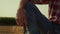 Man leg straw bale in sunlight closeup. Field worker resting on hay stack sunset