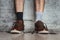 Man legs in brown leather shoes and different socks on a dark background, close up. Concept of strange idiot man