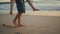 Man legs stepping sand carrying woman at evening beach closeup. Couple piggyback