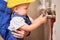 Man and little boy installing plumbing pipes in apartment.