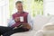 Man in living room with coffee reading newspaper