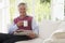 Man in living room with coffee reading newspaper