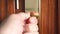 Man locking a bronze door bolt lock close-up on a dark wooden door.