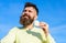 Man with long beard enjoy coffee. Man with beard and mustache on smiling face drinks coffee, blue sky background