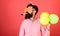 Man with long beard on red background. Bearded man in huge glasses with party whistle, celebration concept. Crazy man