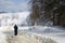 A man in long black clothes walks away towards the snow hill