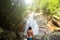 Man with a long hair is enjoy in lagoon of huge tropical waterfall in jungle. Travel concept.