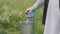 Man in a long shirt pours water from a pump into a metal bucket.