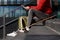 Man longboarder in casual clothes using his smartphone, resting on the steps, sitting with longboard/skateboard outdoors