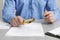 Man looking at document through magnifier at white table, closeup. Searching concept