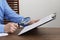 Man looking at document through magnifier at wooden table, closeup. Searching concept