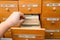 A man is looking for information in a file cabinet. Old wooden card catalog with one open drawer. Database concept