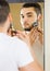 Man looking at mirror and shaving face with razor