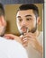 Man looking at mirror and shaving face with razor