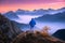 Man looking on mountain valley with low clouds at colorful sunset