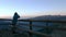 Man looking at mountain view at sunrise from wooden balcony and drinking hot beverage from mug, high up on the Alps