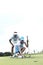 Man looking at woman aiming ball on golf course against sky