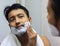 Man lookingIndian asian after his appearance in front of a mirror beauty styling lifestyle. Shaving routine applying foam