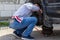 A man looks at the brake pads in car wheel hub with brake disc at tire shop with a flashlight from a smartphone