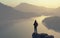 A man looks over the top of the mountain lake and forest.