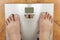 Man looks at a personal scale. Look on her toes, diseased nails. Komcept reducing body weight and dieting.
