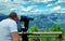 A man looks through a telescope to the mountains