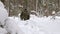 A man lost in a winter forest walks through deep, loose snow.