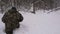 A man lost in a winter forest walks through deep, loose snow.