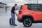 A man with luggage opens the trunk of a car in an open parking lot