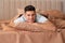 Man lying in bed with brown linens at home