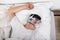 Man Lying On Bed With Sleeping Apnea And CPAP Machine