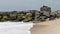 Man lying down sleeping on jetty of rocks while fishing in the ocean