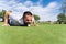 Man lying on a golf course biting a golf ball next to a hole