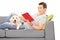 Man lying reading book on sofa with a puppy
