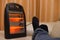 Man lying on sofa with electric heater near his feet