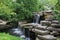 A man made stone waterfall cascading into a pond in a landscaped garden in Wisconsin