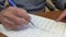 A man makes corrections in entries on a sheet of white paper with a ballpoint pen in blue ink, close-up