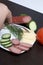 The man makes an easy snack. On the saucer are sausage, cucumber, tomato, cheese and dill.