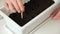 A man makes holes in ground, soil for planting pea sprouts. Preparation seedlings in balcony box.