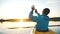 Man makes selfie on smartphone while sitting in kayak on calm lake at sunset, outdoor activities