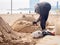 Man is making a dragon sand sculpture on the Sant Miguel beach in Barcelona