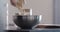 Man making granola pour oat flakes into steel bowl on kitchen countertop