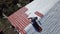 Man making roof of country house. Stock footage. Top view of builder putting metal shingles on roof. Man independently