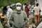 Man In Mask Against Crowd Of Migrants