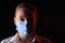 Man in a mask, on a black background with red light. Epidemi, dangerous corona virus 2020. Infection and mass disease. Danger.
