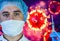 Man in a mask and protective gloves on the background of the image of a coronavirus. Doctor with a vaccine and a syringe