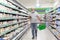 A man in a mask among the shelves with groceries in a supermarket with a phone in his hands. Big choice. Coronavirus pandemic